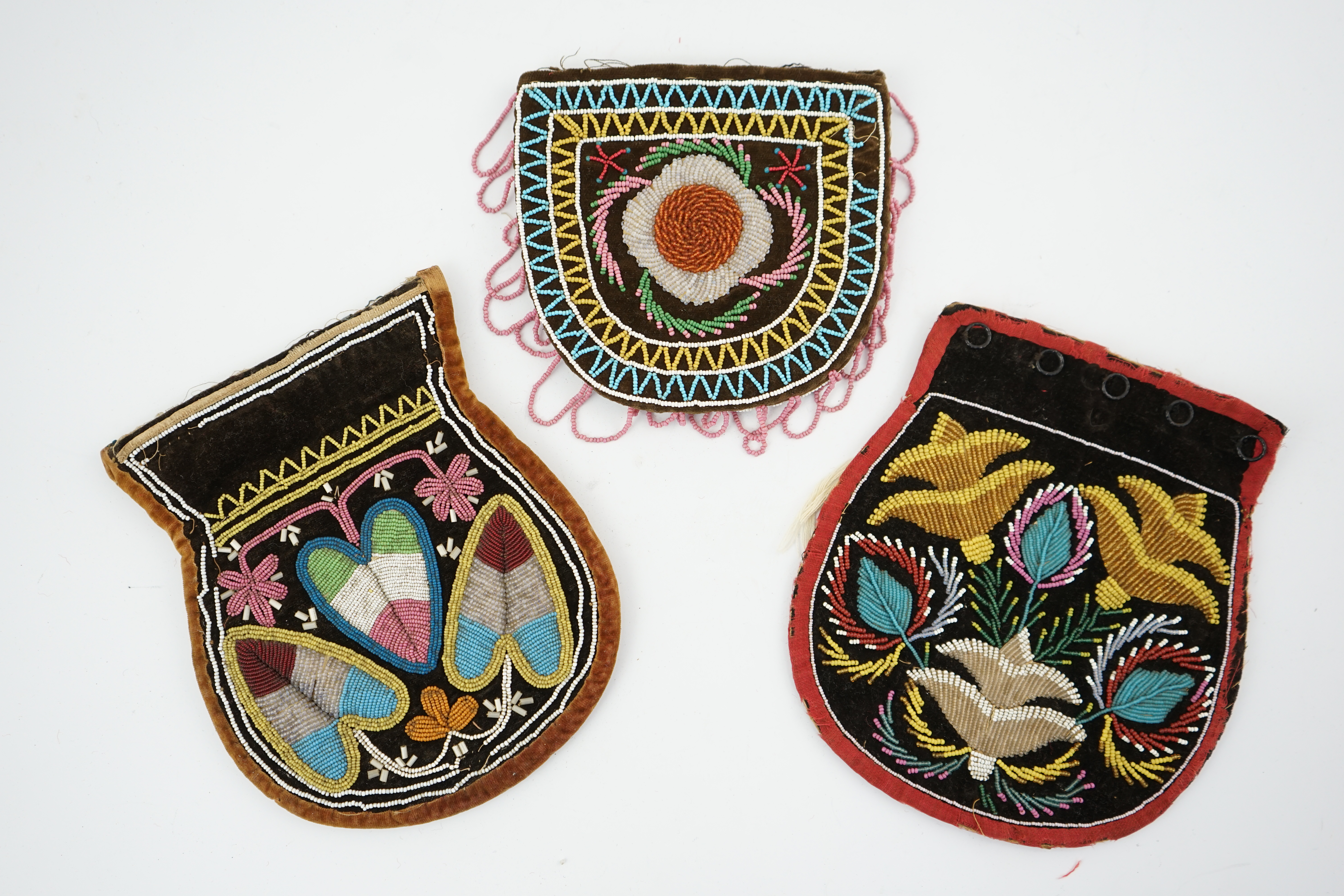 Three 19th century Native American bead worked pouches. A Wabanaki pouch/bag, worked in heart shaped fine coloured beads one side, the other side with flowers and leaves, embroidered on brown velvet, together with two Ir